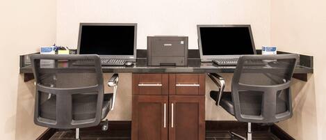 A conference room with three desktop computers, two office chairs, and a printer.