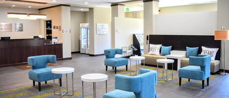 A hotel lobby with a reception desk, seating area, and a large bed with pillows.