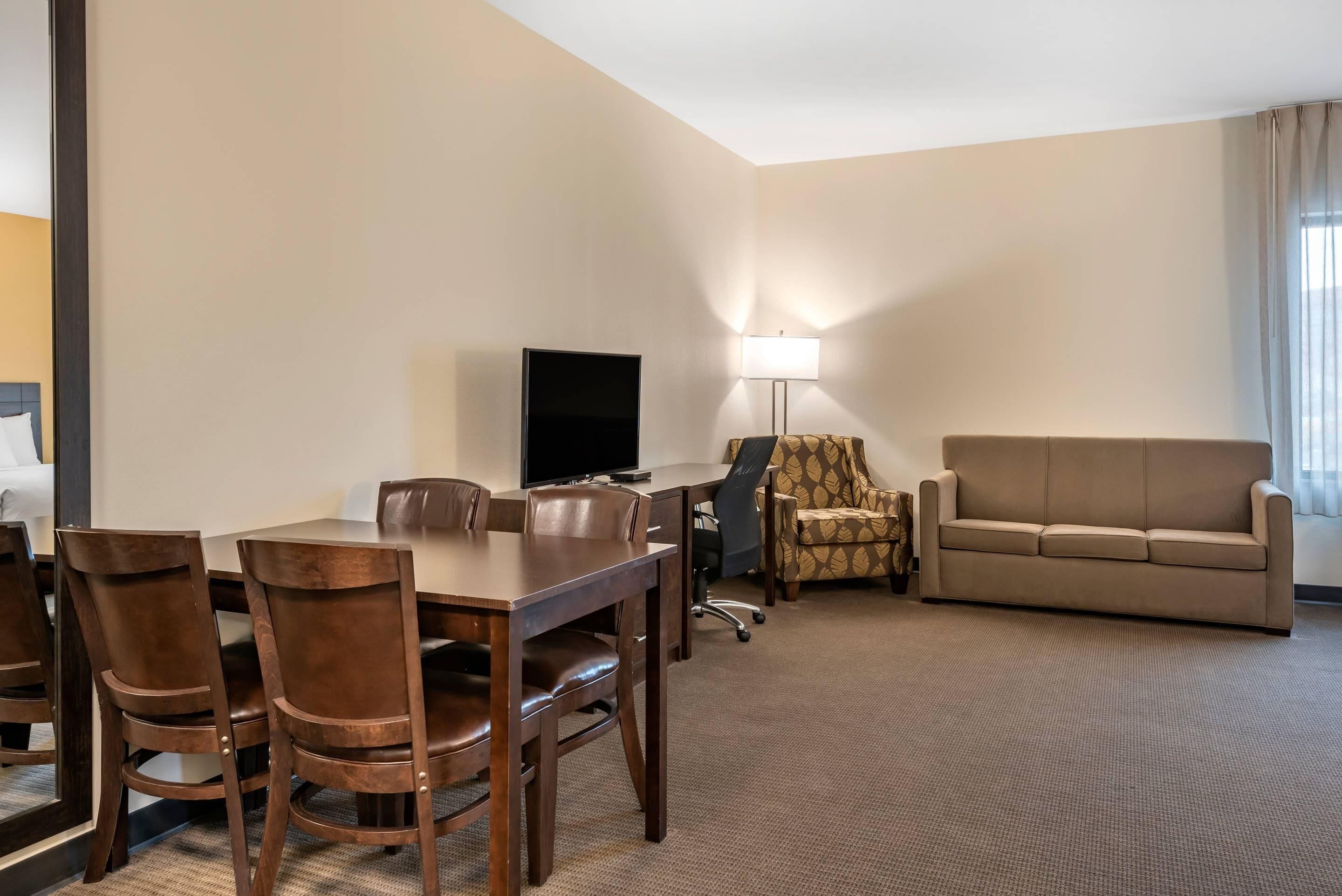 Une chambre d’hôtel équipée d’une table à manger, de chaises, d’un canapé, d’une télévision et d’une lampe.