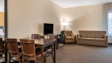 Une chambre d’hôtel équipée d’une table à manger, de chaises, d’un canapé, d’une télévision et d’une lampe.