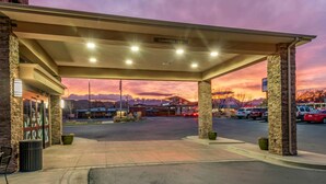 Een tankstation met een overdekt gedeelte, heldere lucht en een zonsondergang op de achtergrond.