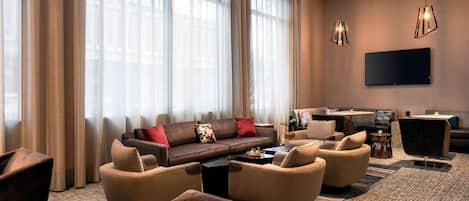 Ein modernes Wohnzimmer mit einem Ecksofa, Sesseln, einem Couchtisch und einem flachbildfernseher an der Wand.