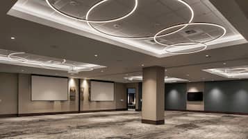 A spacious conference room with a patterned carpet, a large screen, and modern circular ceiling lights.