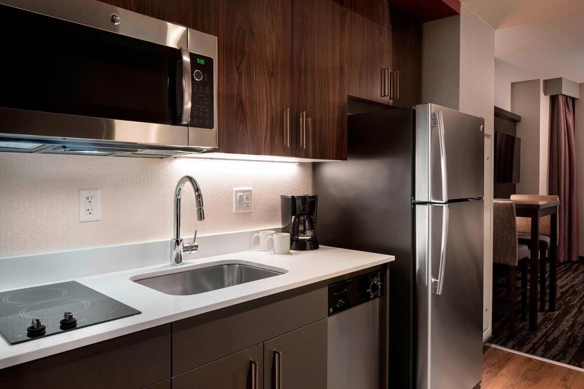 A modern kitchen with stainless steel appliances, a double sink, and wooden cabinets.