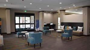 A hotel lobby with a reception desk, seating area with sofas and chairs, a piano, and a large window. - Sleep Inn & Suites Moab near Arches National Park (Moab)