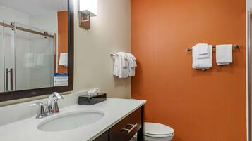 A bathroom with a white sink, a mirror, a toilet, and two towel racks with white towels.