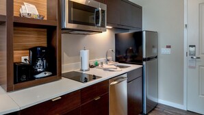 Una cocina moderna con un refrigerador de acero inoxidable, un microondas integrado y una cafetera.