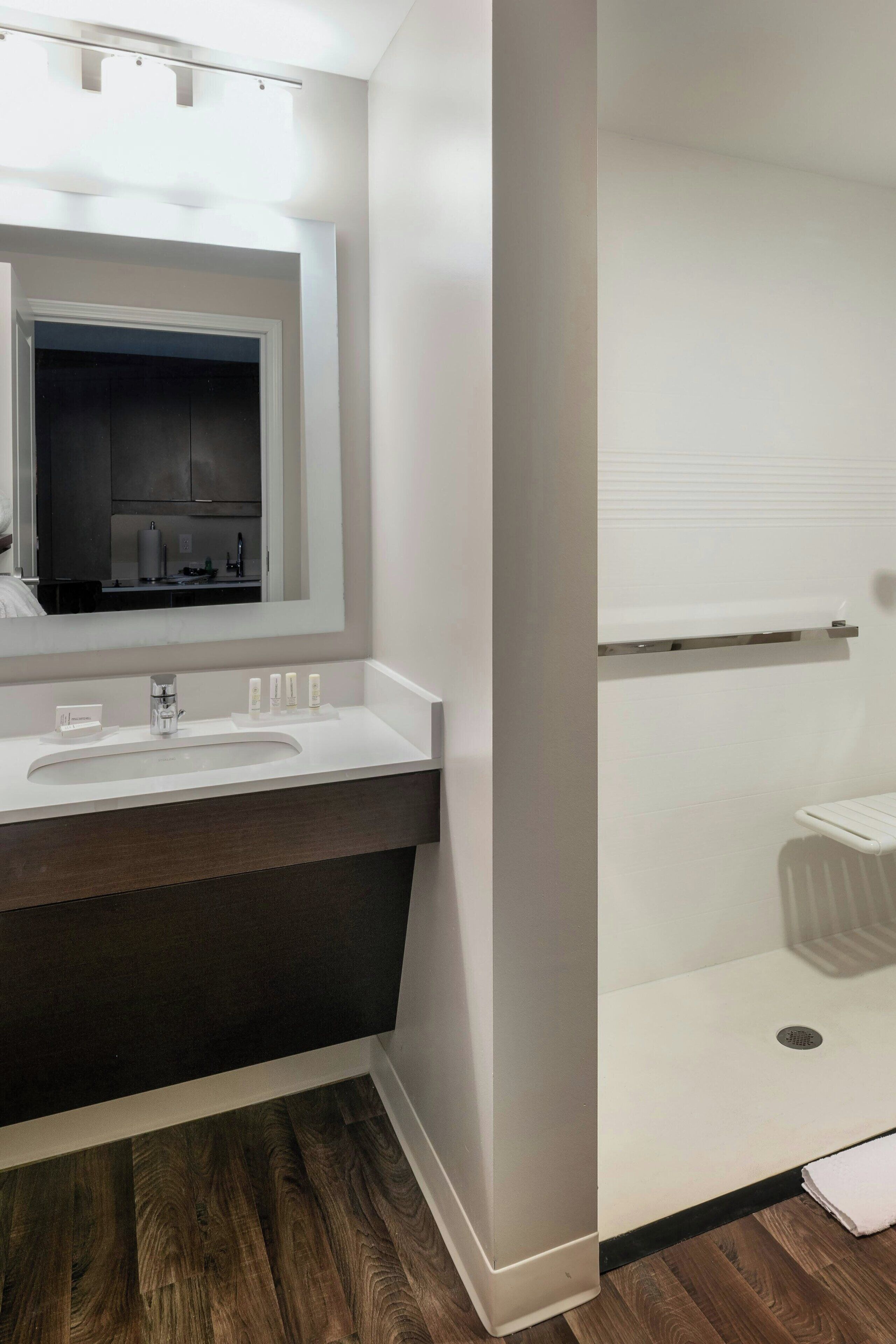 A modern bathroom with a white vanity, a large mirror, and a shower area.