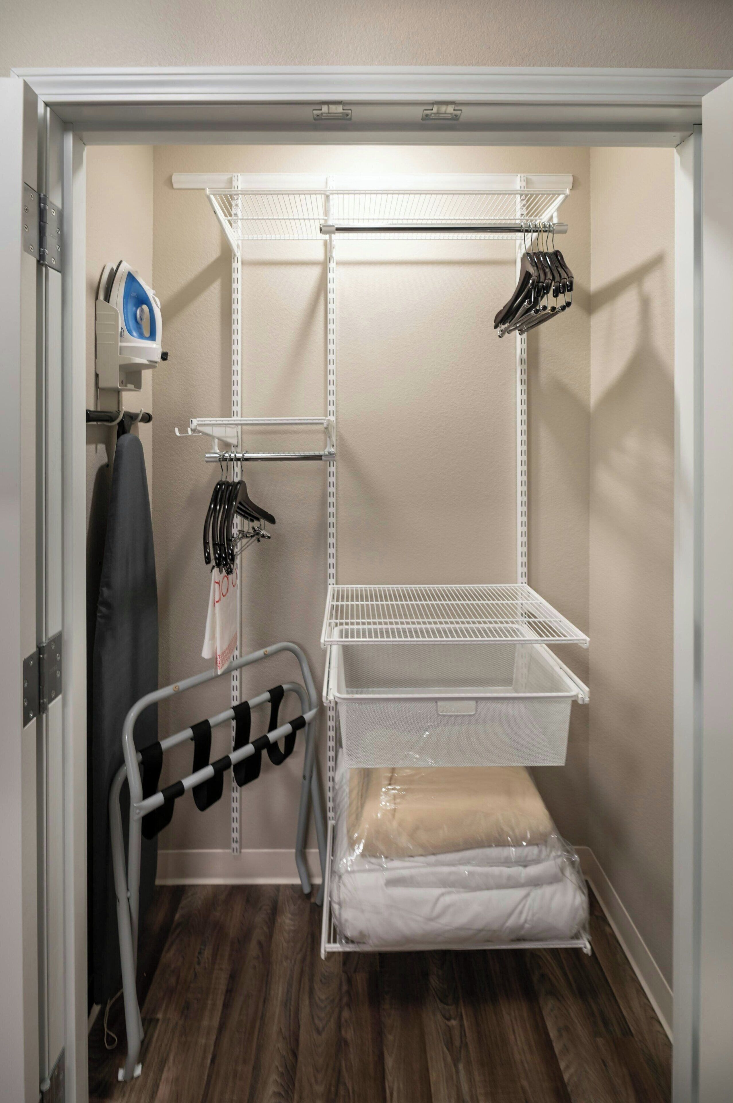 En walk-in-garderob med hyllsystem i metall, en klädstång och en förvaringslåda.