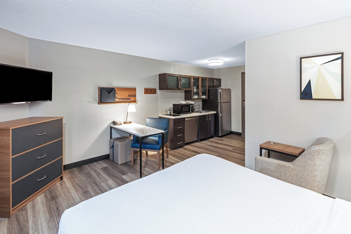 Une chambre d’hôtel équipée d’un lit, d’un bureau, d’une chaise, d’une kitchenette et d’un téléviseur.