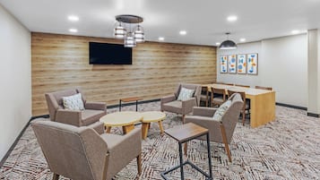 Uma sala de conferências moderna com parede de madeira, TV de tela plana e piso coberto por carpete.