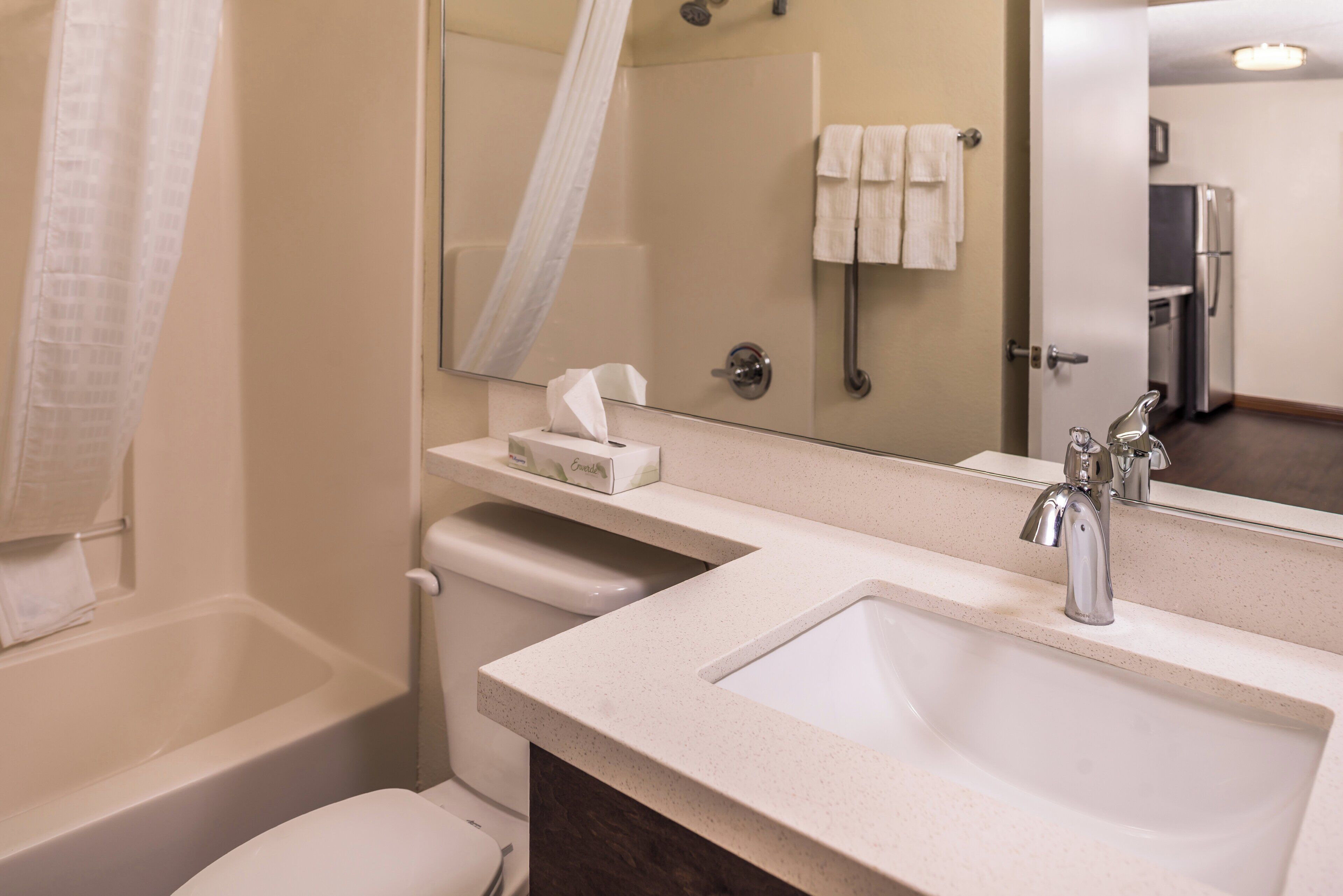 Un baño con bañera, inodoro y lavabo con espejo arriba.