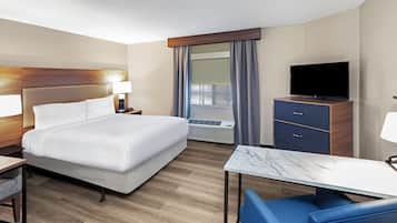 A hotel room with a bed, a desk, a TV, and a window with curtains.
