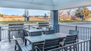 An outdoor patio with a grill station, tables, and chairs.