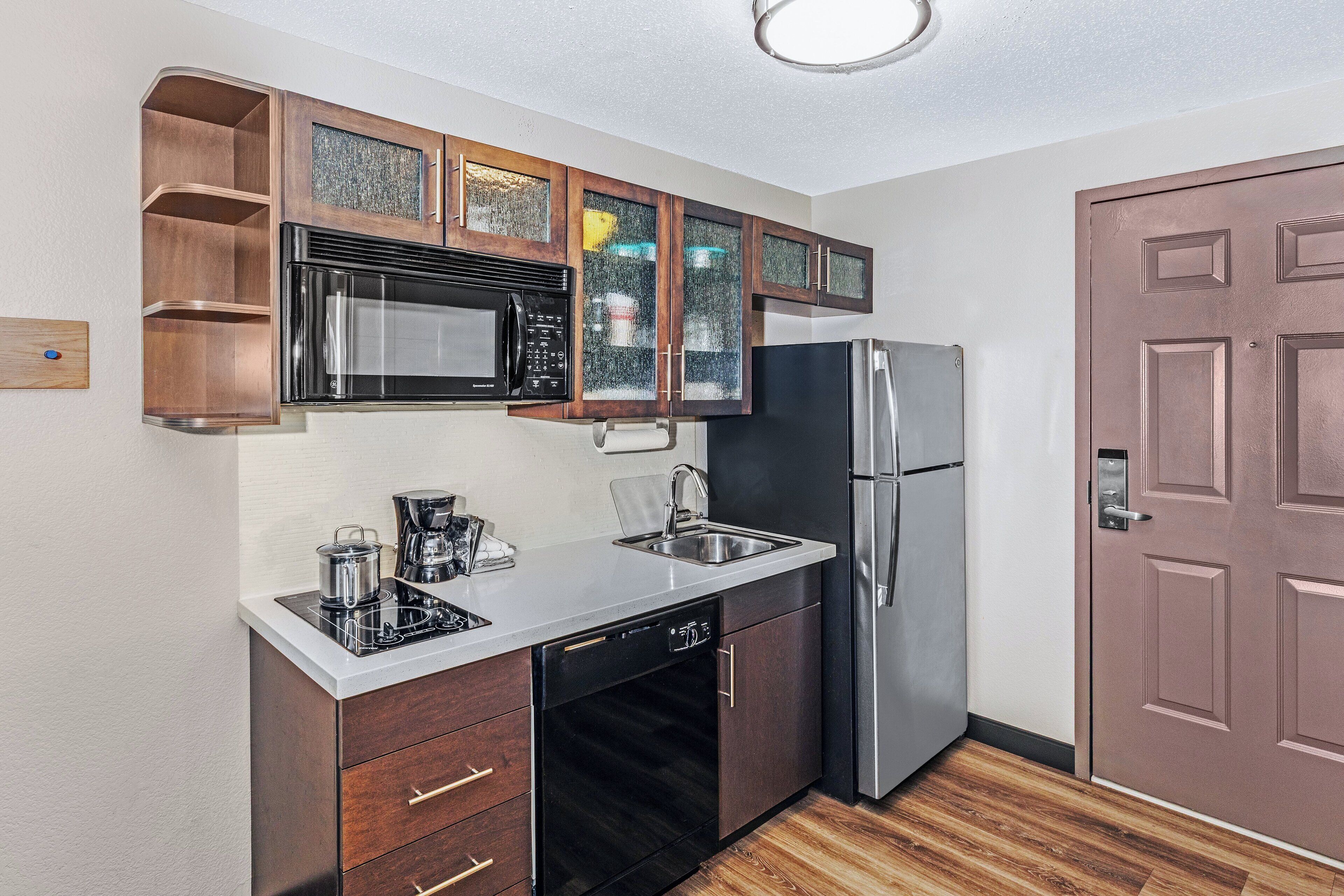 Una cocina compacta equipada con microondas, estufa, fregadero y refrigerador.
