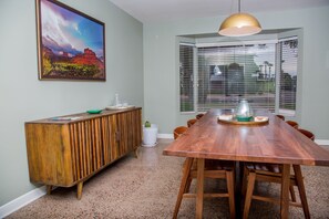 A dining room with a wooden table, chairs, a cabinet, and a large window with blinds. - Encanto Vistas, A Golf Property in Central Phoenix (Phoenix)