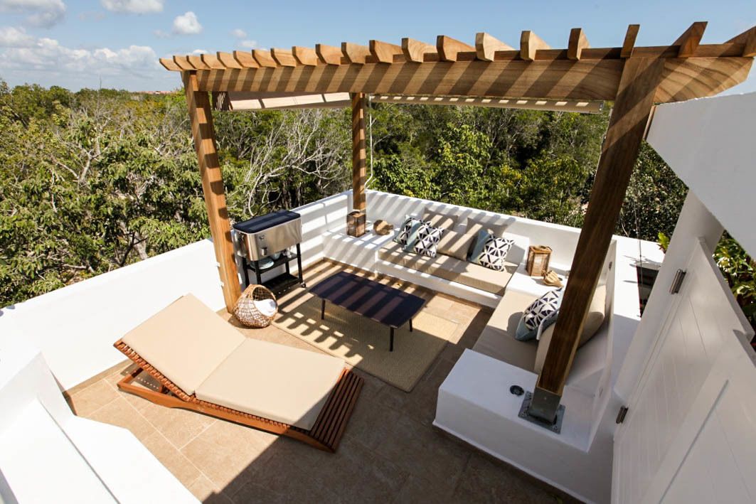 An outdoor patio with a pergola, seating area, and a built-in grill.