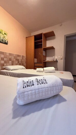 Ein Hotelzimmer mit zwei Betten, einem Kleiderschrank und einem Badezimmer.