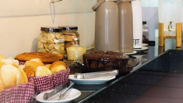 A buffet with various food items, including pastries, a chocolate cake, and condiments.