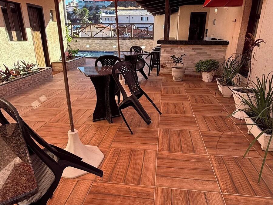 Un patio con piso de madera, mobiliario exterior y sombrillas rojas.