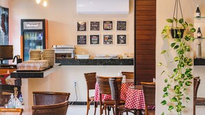 A restaurant interior with wicker chairs, a checkered tablecloth, a hanging plant, and a wall-mounted air conditioner. - Hotel Italia Beach (Natal)