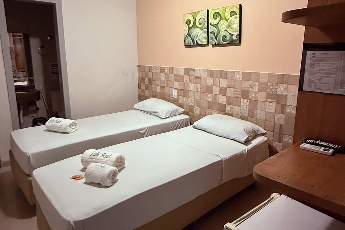 Una habitación de hotel con dos camas, un refrigerador pequeño y una pared decorada con azulejos.