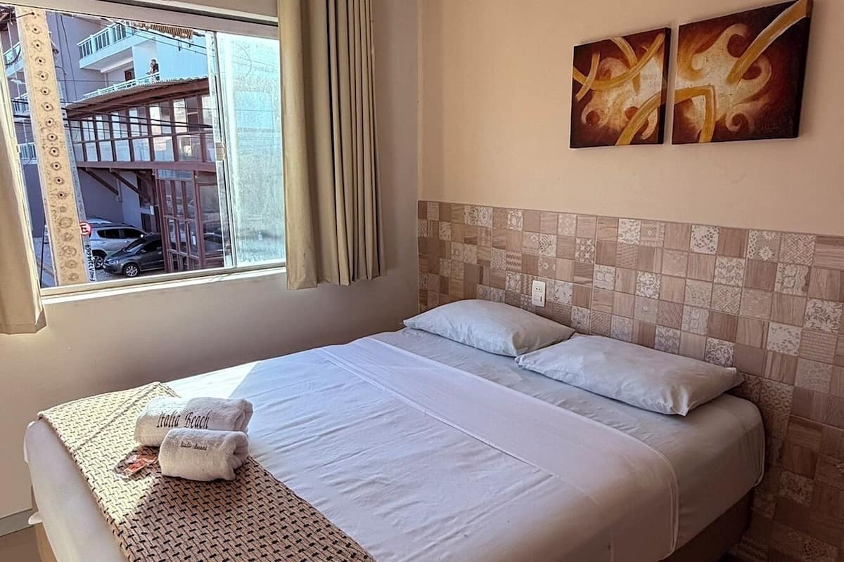 Una habitación de hotel con una cama grande, vistas al exterior y dos obras de arte colgadas en la pared.