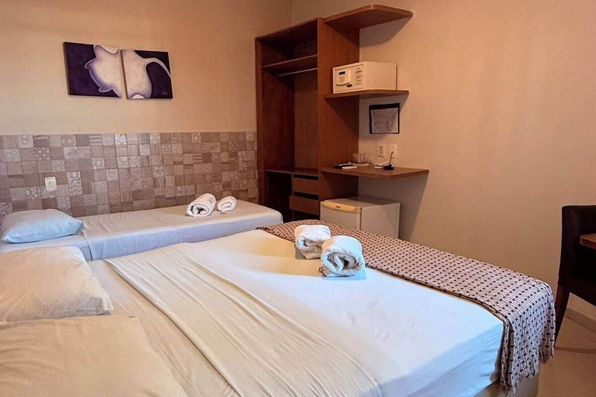 Habitación de hotel con dos camas, un escritorio pequeño, microondas y una obra de arte en la pared.