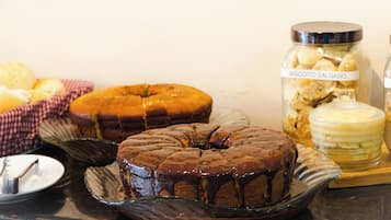 Un gâteau au chocolat en forme de couronne, présenté sur une assiette en verre, un bocal de biscuits secs et un bocal de glaçage au beurre.