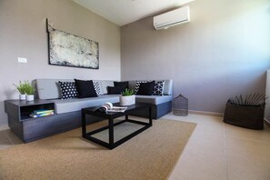 A modern living room with a grey sofa, black and white patterned cushions, a black coffee table, and a large abstract painting on the wall. - Tony Condo 2 bedroom sleeps 4 (Tulum)