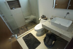 Un baño moderno con ducha, inodoro, lavamanos y armarios de almacenamiento.
