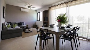A modern living room with a sofa, coffee table, and dining table with chairs. - Tony Condo 2 bedroom sleeps 4 (Tulum)