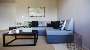 A modern living room with a grey sofa, black and white patterned pillows, a black coffee table, and a wall-mounted abstract painting. - Tony Condo 2 bedroom sleeps 4 (Tulum)