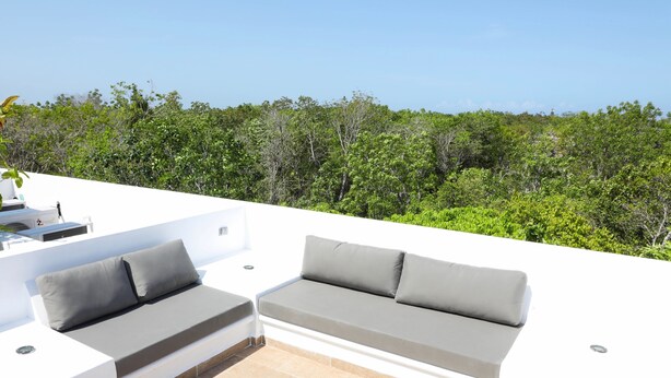 A rooftop patio with a white outdoor sofa and a round wooden table. - Martiki Condo 2 bedroom sleeps 4 (Tulum)