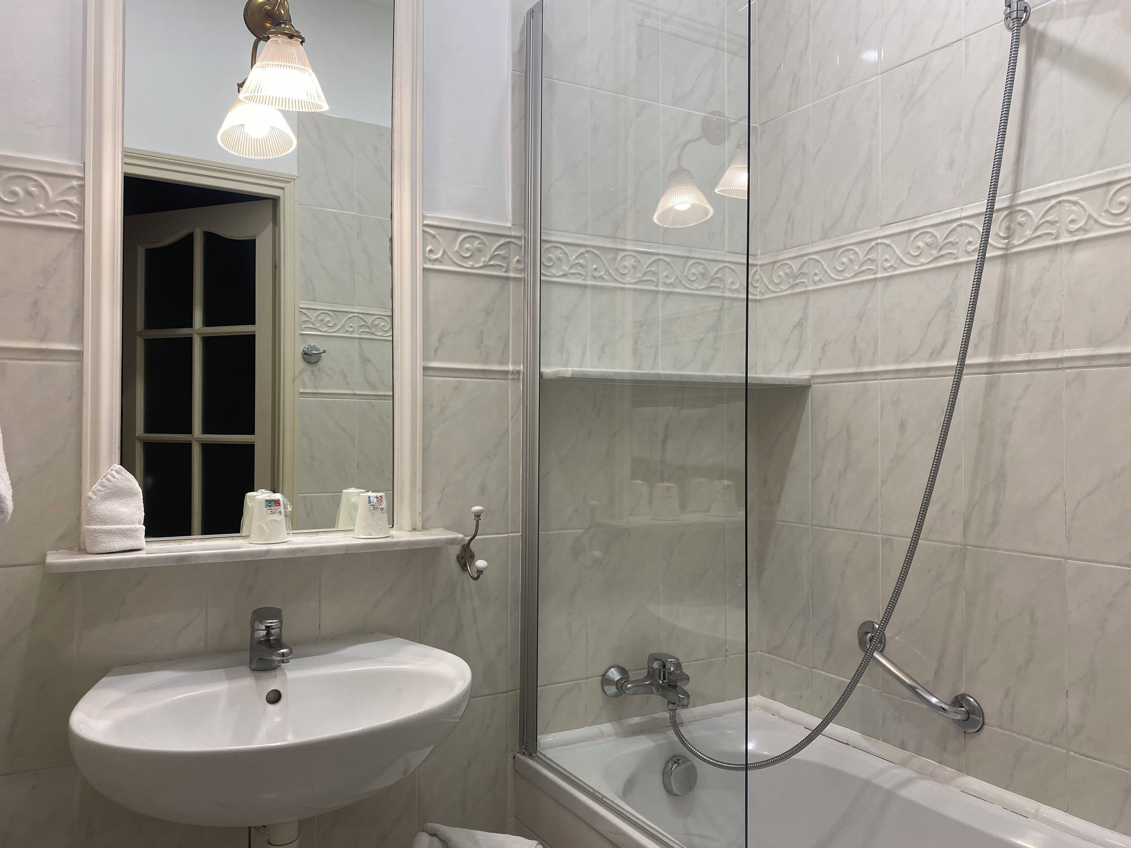 Un bagno con un lavandino bianco, una doccia con pareti in vetro e uno specchio con cornice decorativa.