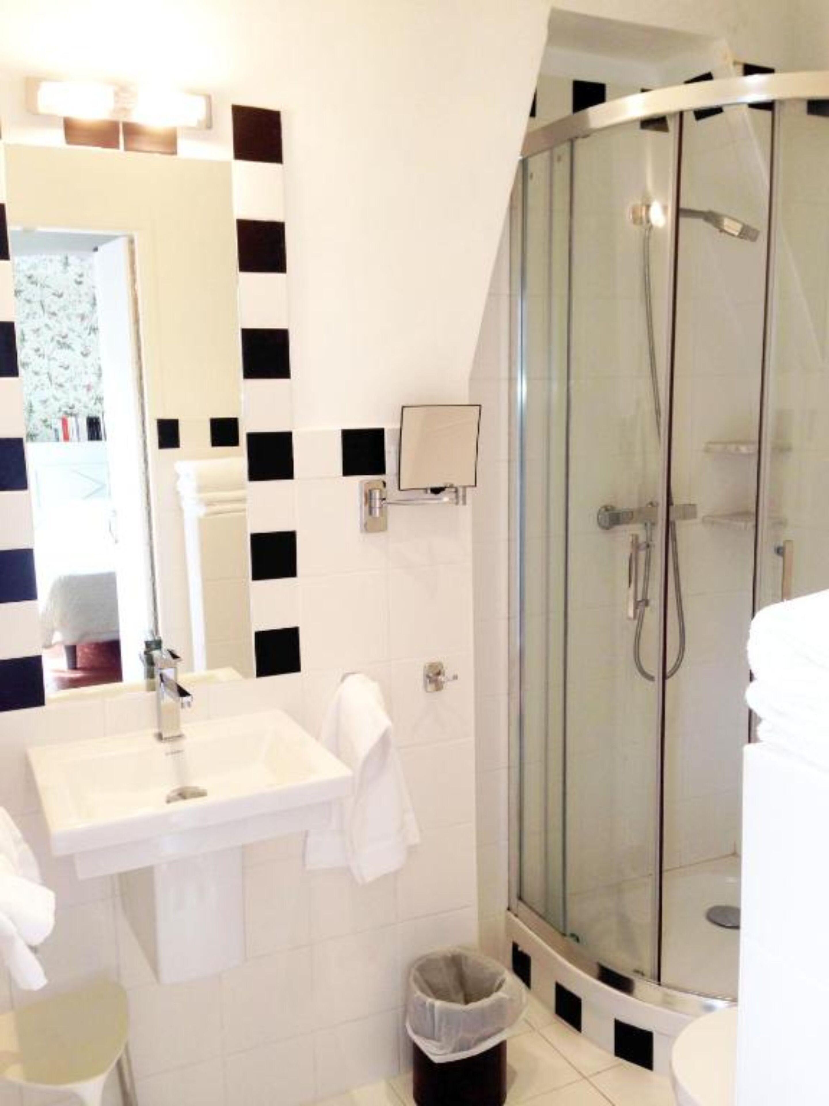 Une salle de bain moderne avec un lavabo blanc, un miroir et une douche en verre.