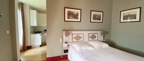 A bedroom with a bed, a bedside telephone, and a wall-mounted light fixture.
