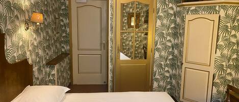 Habitación de hotel con una cama, dos puertas, un armario y una pared con un diseño de hojas.