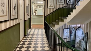 A hallway with a checkered floor, striped walls, and framed artwork on the walls. - Hotel Central Bastia (Bastia)