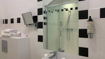 A modern bathroom with a glass-enclosed shower, a sink with two faucets, and a mirror mounted on the wall.