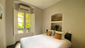 A bedroom with a large bed, a window with shutters, and a built-in shelf above the bed. - Hotel Central Bastia (Bastia)