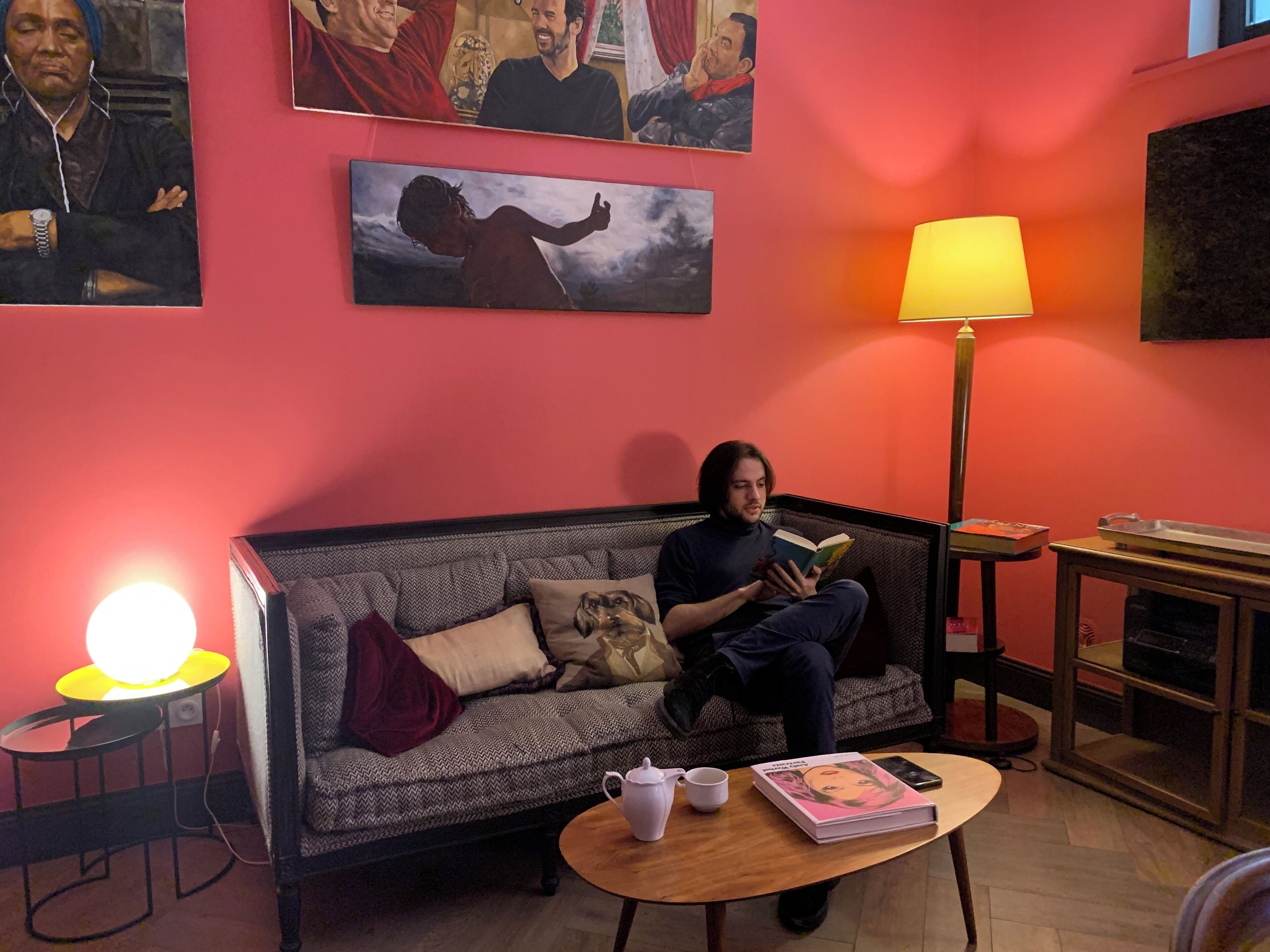 Un accogliente soggiorno con un divano, un tavolino da caffè con un libro e una teiera, e una lampada.