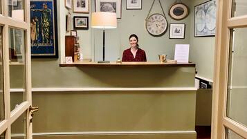 A reception desk with framed pictures, a clock, and a lamp.