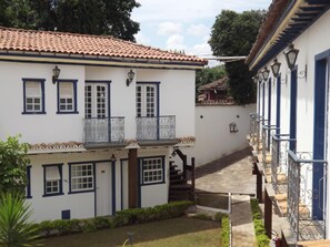A white building with blue trim, a tiled roof, and a small balcony with metal railings. - Pousada Mãe D'Água (Tiradentes)