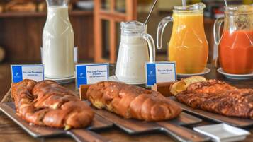 A breakfast buffet with various bread options and beverages.