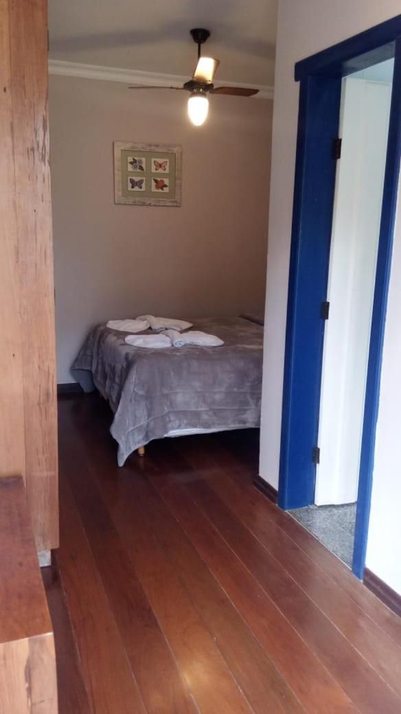 A bedroom with a bed, a ceiling fan, and a door with a blue frame.