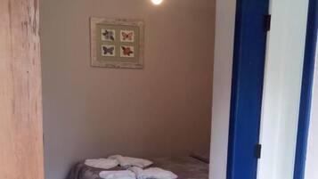 A bedroom with a bed, a ceiling fan, and a door with a blue frame.
