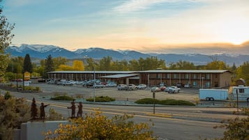 A building with a parking lot and a mountainous backdrop.