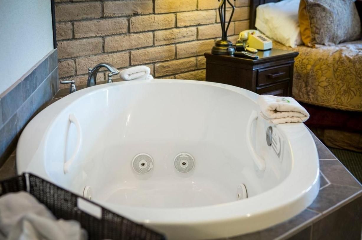 Une salle de bain avec une baignoire blanche, une serviette et un mur en briques.