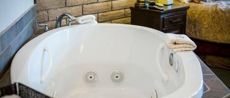 Une salle de bain avec une baignoire blanche, une serviette et un mur en briques.